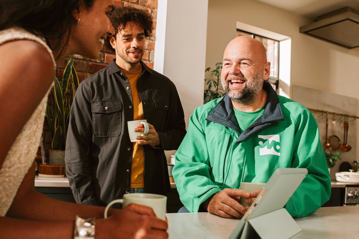 An OVO engineer comparing rates on a tablet with two homeowners in a kitchen