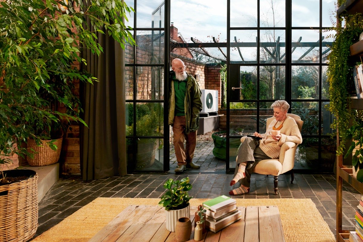 Two homeowners in a glazed garden room looking out onto a brick courtyard