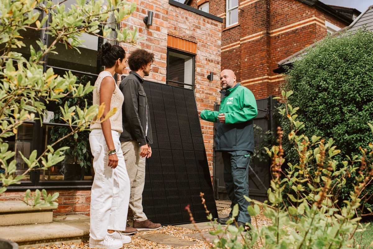 An OVO partner showing a solar panel to homeowners outside their house